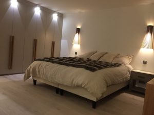 Chambre avec lit double et appliques en bois moderne