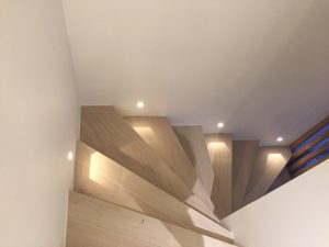Escaliers en bois descendants avec spots encastrés au mur